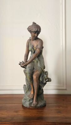 une statue représentant une femme assise sur une souche d'arbre