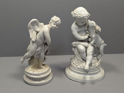 deux statues blanches représentant des anges, posées sur un socle