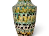 un vase vert et jaune posé sur une surface blanche