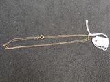a close up of a gold chain with a heart on it