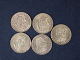 six pièces d'argent de tailles et de formes différentes sur un fond bleu