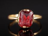 gros plan d'une bague en or avec une pierre rouge