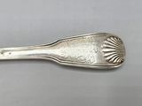 silver spoon with a design on it on a gray surface