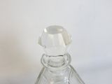 une bouteille en verre transparent avec un bouchon transparent, posée sur une surface blanche