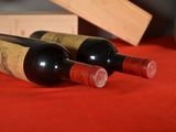 two bottles of wine sitting on a red table cloth