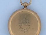 a small gold pocket watch with a flower on it