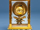 a gold clock with a green marble base on a blue background