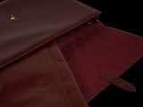 burgundy leather laptop case with gold hardware on top of a black background