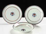two plates and a bowl sitting on a table with a black background