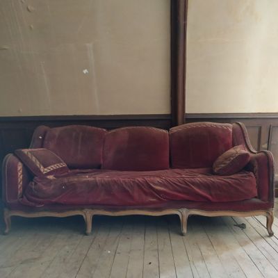 un canapé rouge posé dans une pièce au sol en parquet