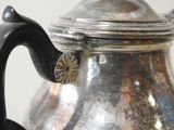 a silver tea pot with a handle on a table