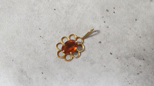 Pendentif fleur en or 750‰, serti d’une pierre orange. En règle. ...