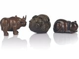 three bronze figurines of rhinos and a rhino on a white surface