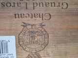 a wooden box with a label on it and a bottle of wine in the background