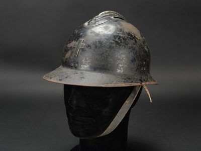 un vieux casque de pompier posé sur la tête d'un mannequin, sur fond noir