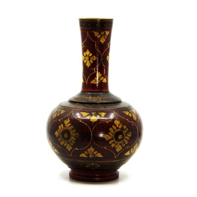 un vase rouge orné de motifs dorés sur fond blanc
