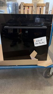 a black oven sitting on a cart in a warehouse