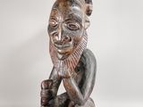 a wooden statue of a man with a beard sitting on his knees