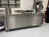 un grand plan de travail en inox sur lequel sont posés des casseroles et des poêles