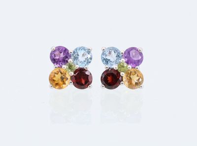 une paire de boucles d'oreilles en pierres multicolores et en argent posées sur un fond blanc
