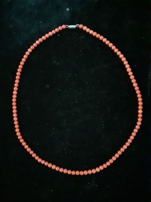 a coral beaded necklace with a silver clasp on a black background
