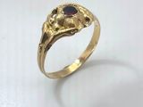 a close up of a gold ring with a red stone