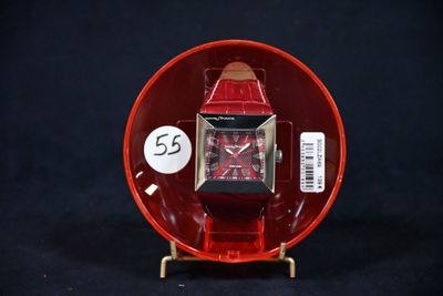 une montre rouge posée sur un objet rouge, sur un fond noir