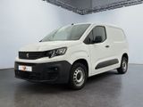 La camionnette blanche est garée dans une grande pièce au sol noir.