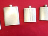 four silver flasks lined up on a red surface