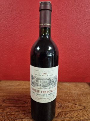 a bottle of red wine sitting on top of a wooden table