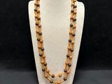 a wooden beaded necklace on a mannequin with a black background