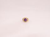 gros plan d'une bague en or avec une pierre violette