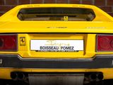 a yellow sports car parked in front of a brick wall