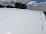 a white van parked in a parking lot with clouds in the background