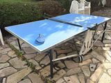 une table de ping-pong bleue sur une terrasse en pierre
