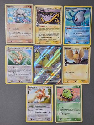 Plusieurs cartes Pokémon sont disposées sur une table devant un réfrigérateur.