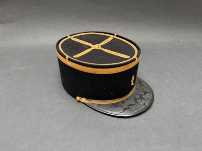 chapeau noir et doré orné d'un ruban doré posé sur une pièce de monnaie