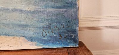 une peinture représentant une scène de plage posée sur une table en bois