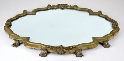 un miroir aux formes ouvragées posé sur une surface blanche, avec un fond blanc