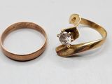 two gold rings and a diamond ring on a white surface