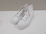 white sneakers with white laces on them sitting on a white surface