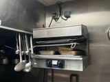 une cuisine en acier inoxydable avec des casseroles et des poêles suspendues au plafond