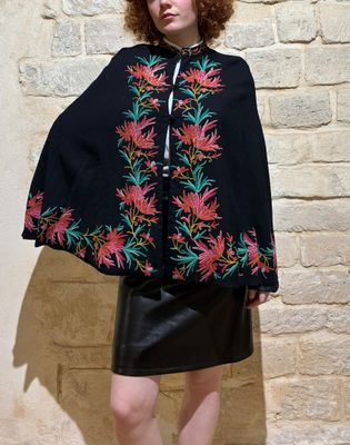 woman wearing a black cape with colorful flowers on it