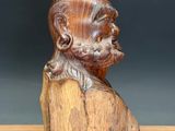 a wooden bust of a man with a beard on a wooden table