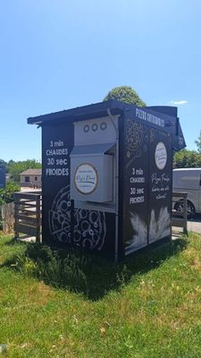 une cabane de toilettes noire avec des graffitis sur le côté
