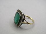a close up of a ring with a green stone in it