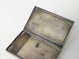 an old silver cigarette case sitting on top of a white table