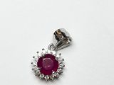 un gros plan d'un pendentif en rubis et diamants posé sur une surface blanche
