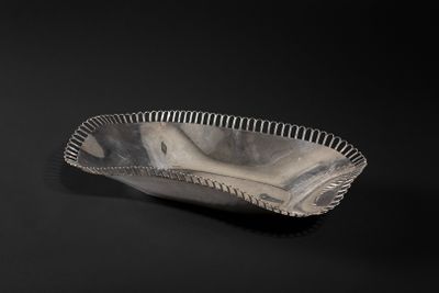 an old silver bowl on a black surface with a black background