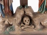 a statue of jesus on a cross with a skull in the foreground